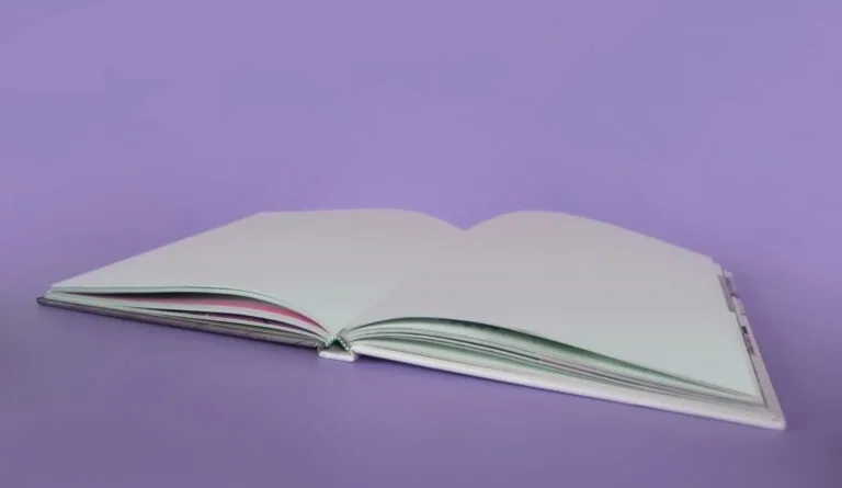 Open blank notebook with white pages against purple background