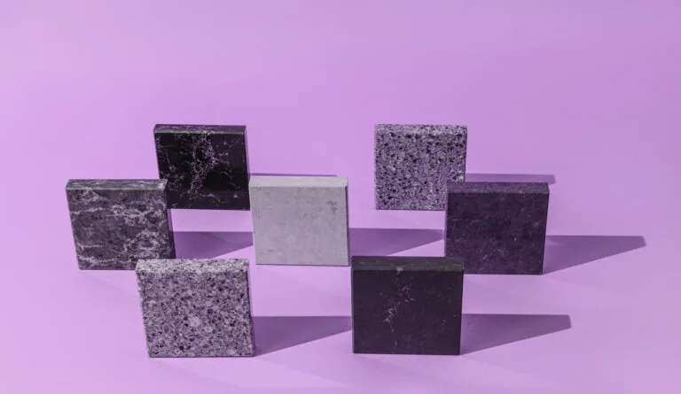 Arrangement of textured stone and concrete blocks in varying shades of gray and purple against a purple background