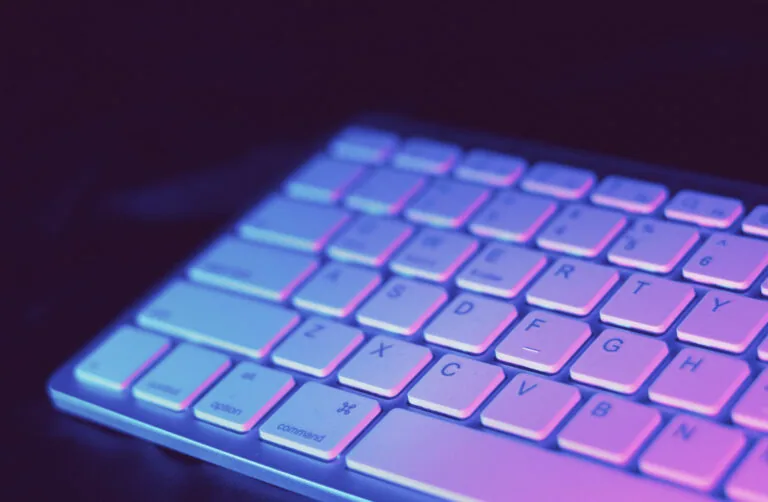 Backlit keyboard with blue and pink neon lighting in dark environment